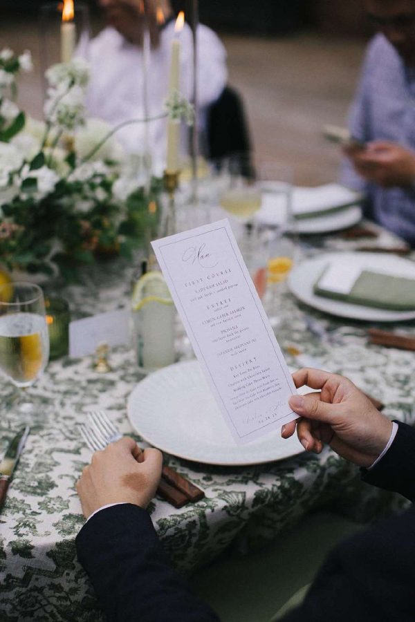 A table setting with a gentleman holding a menu card