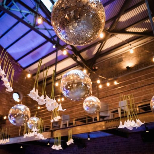 Inside The Foundry's main reception room, string lights and multiple mirror balls hang from the ceiling. Additionally, Rose Hip Social provided the white calla lilies suspended overhead.