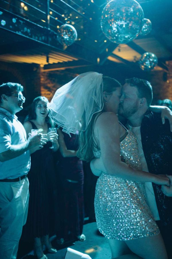 Sophie and David are dancing in the main room at the Foundry under mirror balls with a turquoise color wash.